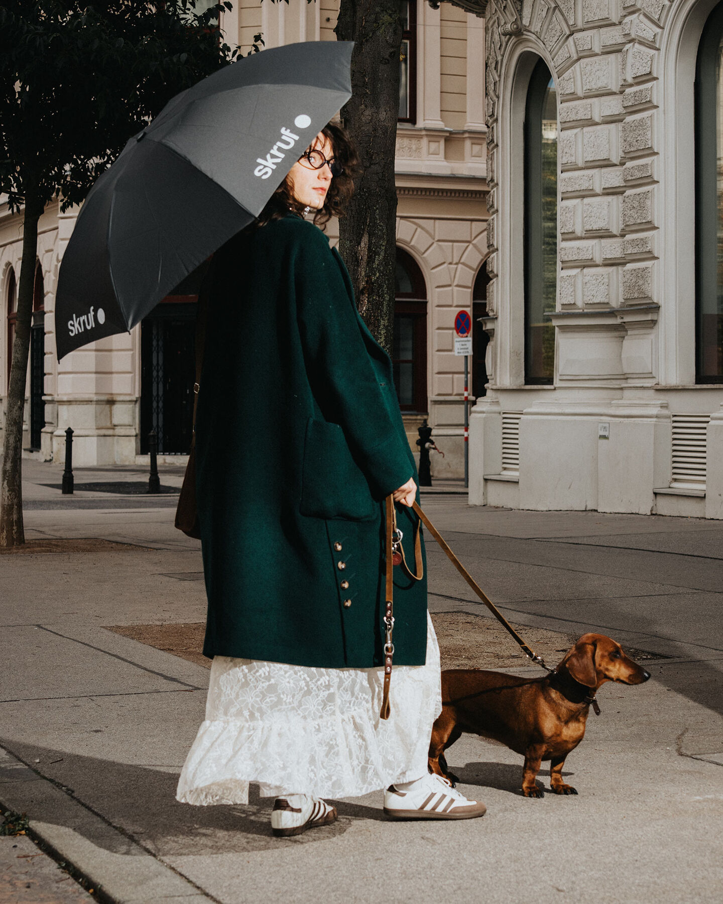 Person mit skruf Regenschirm geht mit kleinem Hund in der Stadt