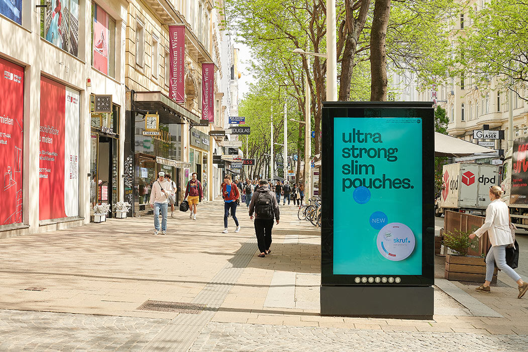Digitale Werbetafel für „ultra strong slim pouches“ in einer belebten Einkaufsstraße.