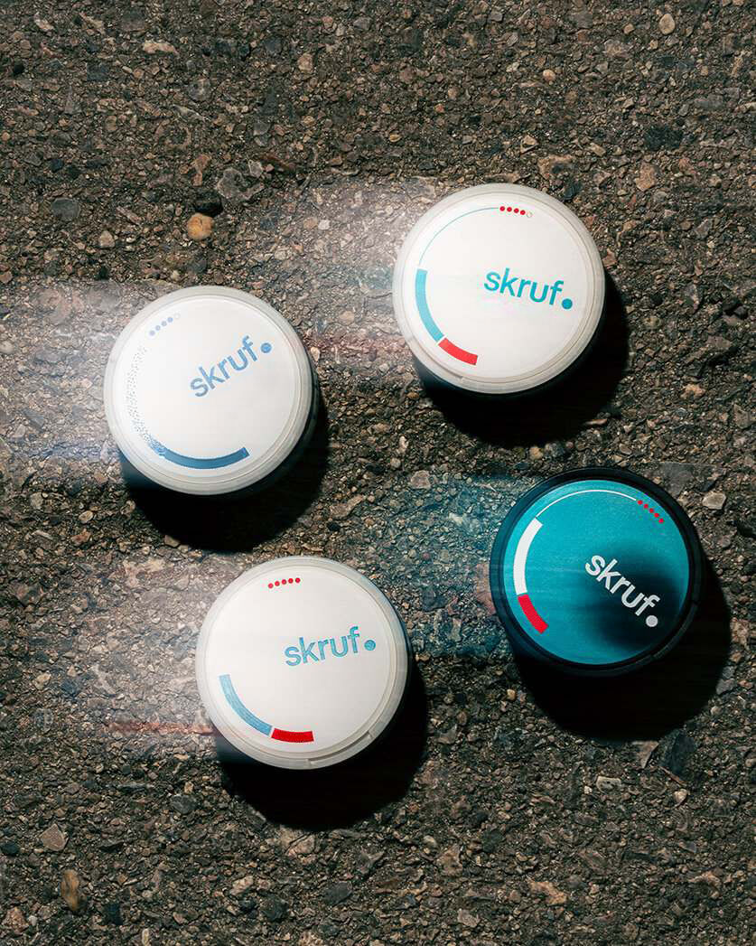 Produktvergleich auf Asphalt: Vier verschiedene skruf Dosen, darunter Superwhite Crystal Fresh, Fresh Xtra, Fresh Freeze Ultra und Intense Formula Peppermint Ultra, im direkten Vergleich.