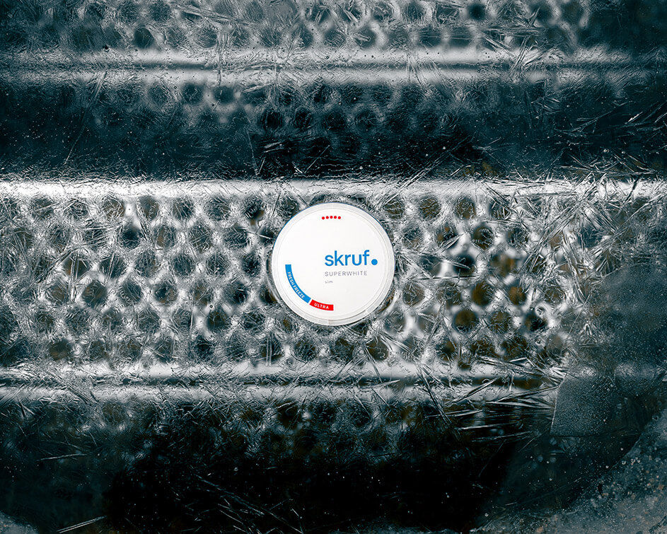 Skruf Superwhite Dose auf einer eisbedeckten Oberfläche mit markantem Muster.