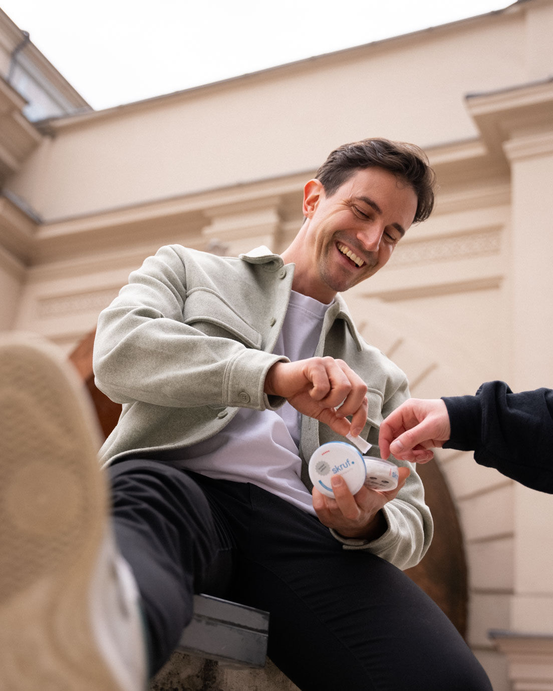 Lachender Mann hält skruf.-Dosen und stößt mit Freund die Fäuste.