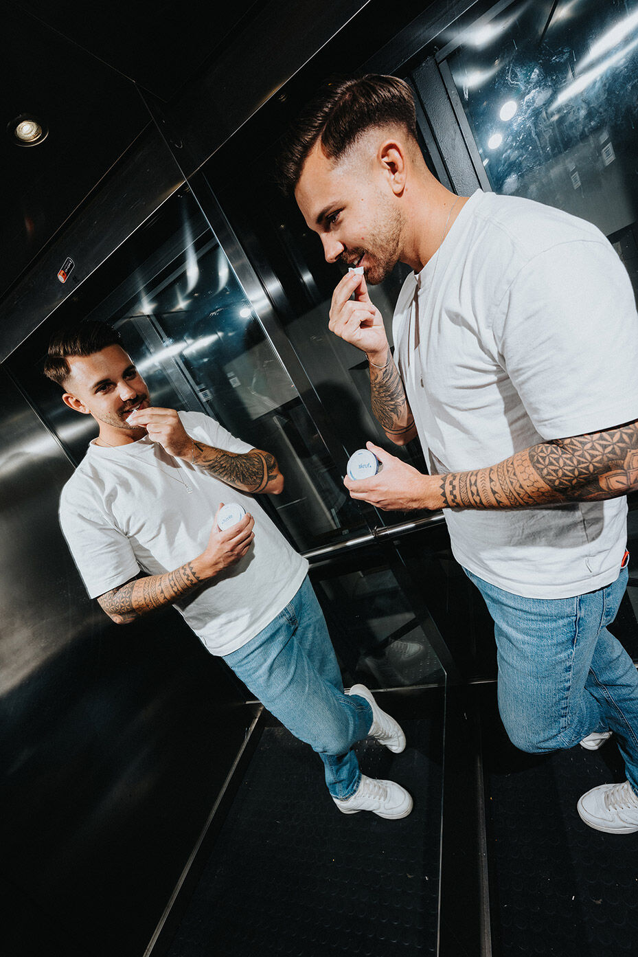 Junger Mann platziert einen skruf Nikotinbeutel im Mund während er vor einem Spiegel steht.