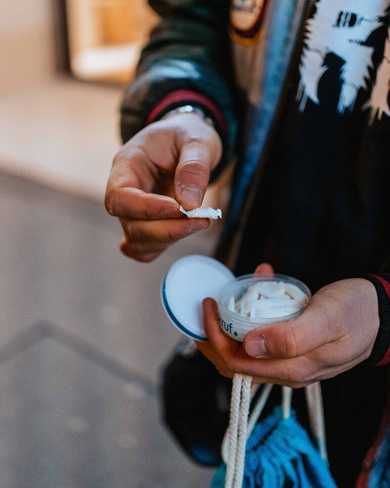 Mann hält Nikotinbeutel in der rechten Hand. In der linken Hand hält er die voll skruf Dose und den Deckel.