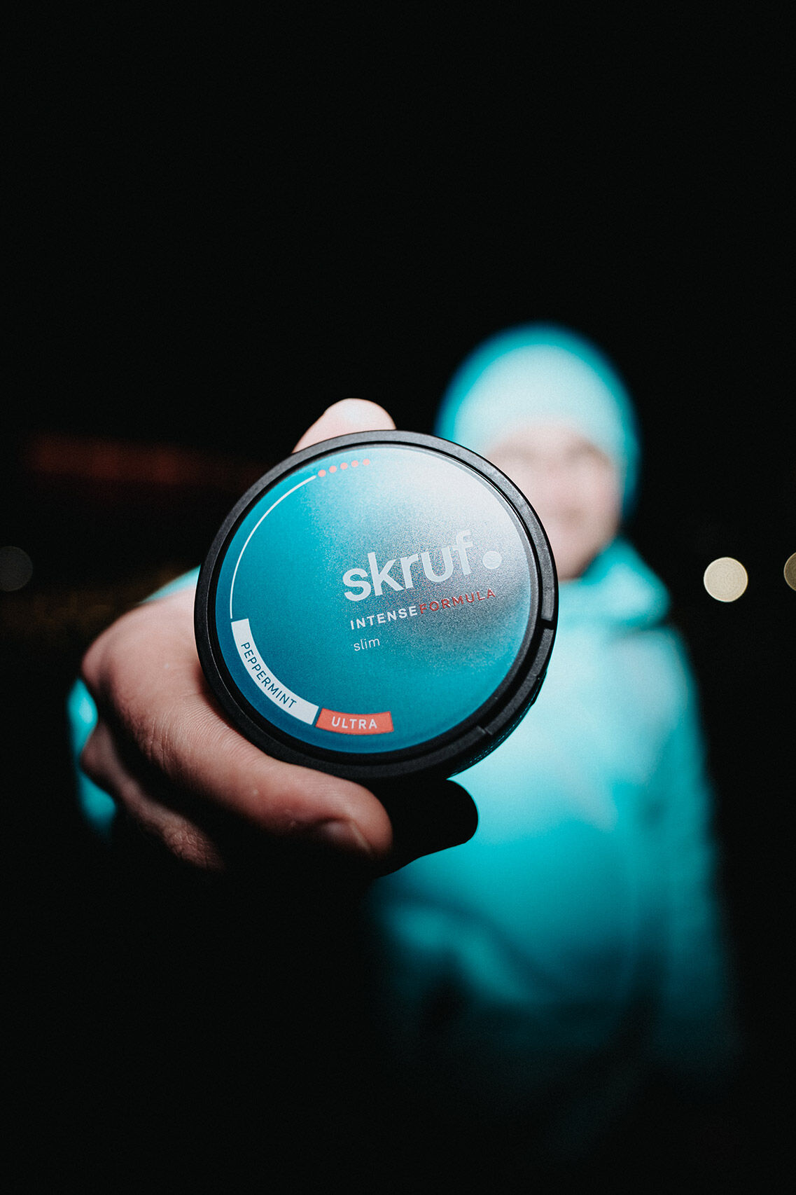 Mann mit blauem Pullover und blauer Haube hält eine skruf intense formula Dose in die Kamera