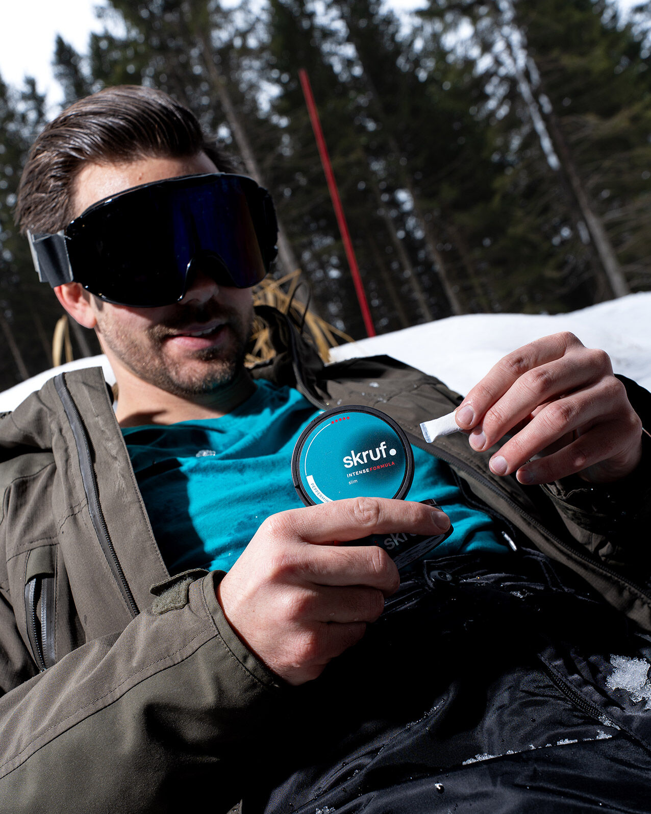 Mann mit Skibrille nimmt einen Nikotinbeutel aus der skruf Dose.
