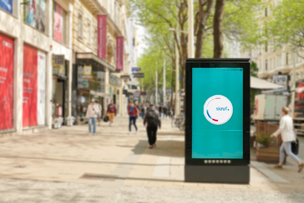 Digitale Werbetafel für skruf in einer belebten Einkaufsstraße.