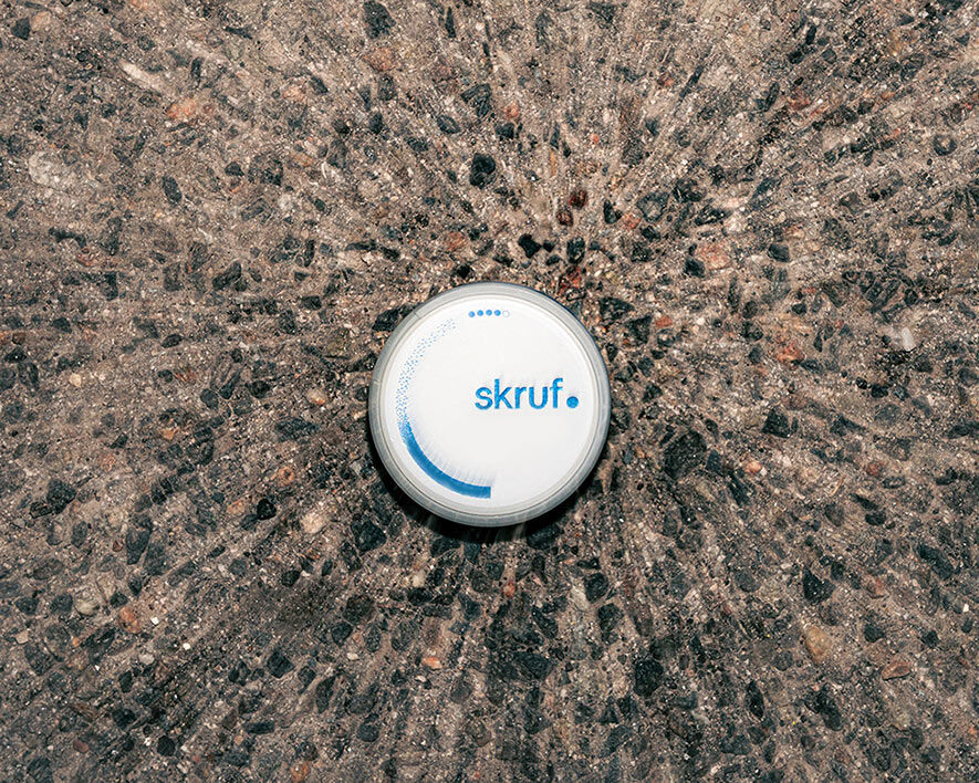 Draufsicht auf eine skruf Dose auf grobem Asphalt.