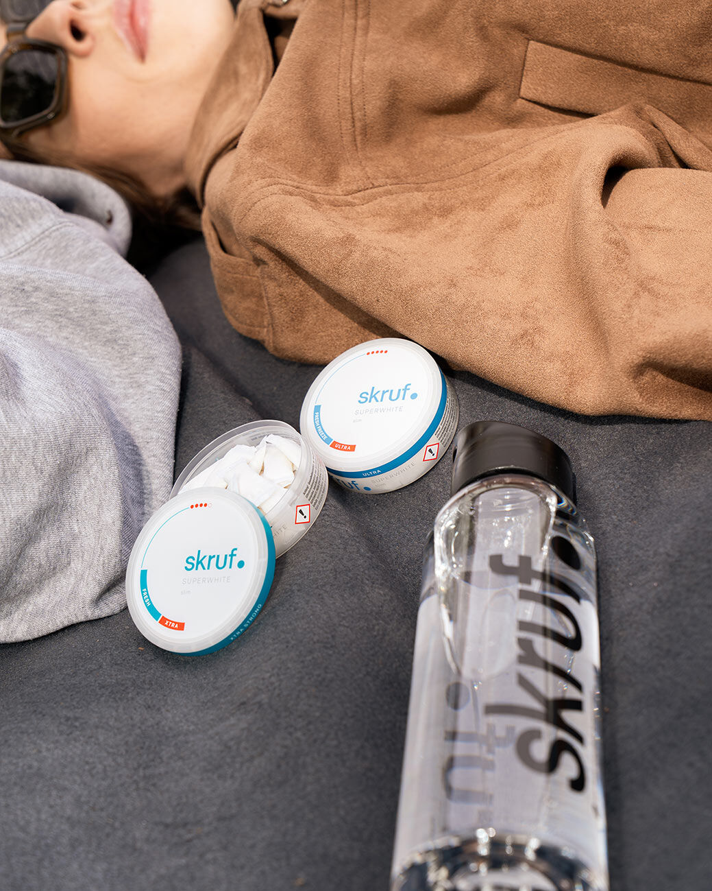 Slim Pouches und Trinkflasche liegen neben zwei Personen auf einer Decke.
