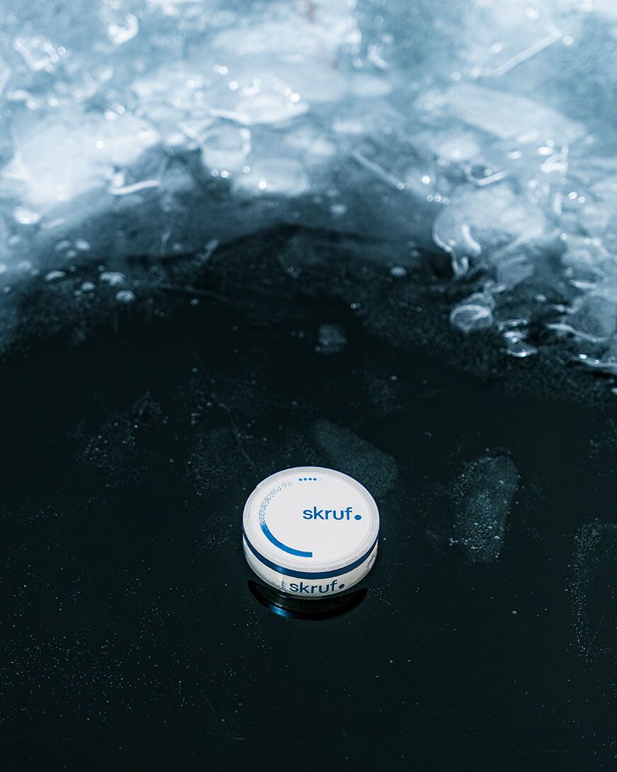 Skruf Superwhite Dose auf Eis mit reflektierender Oberfläche.