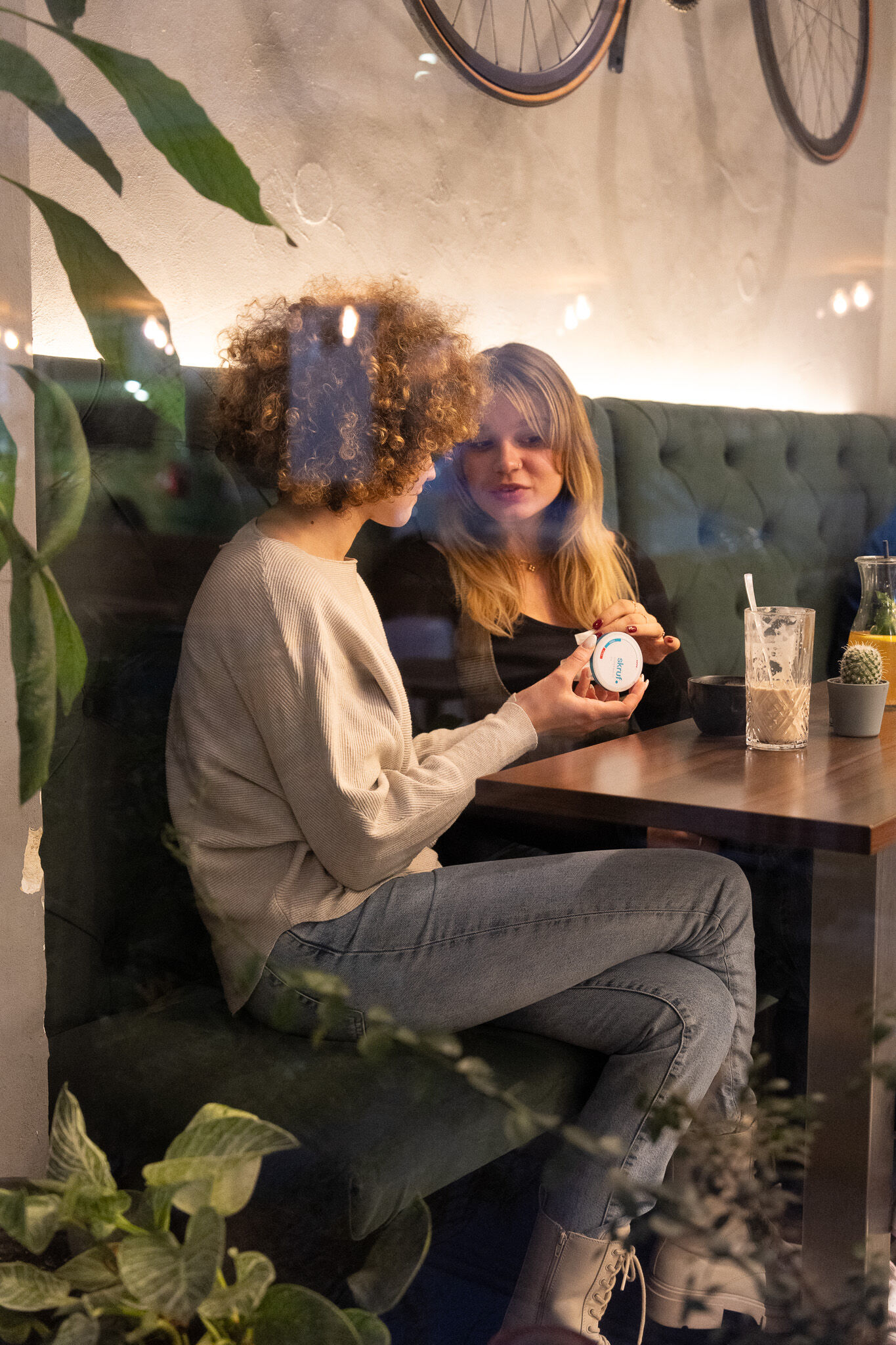 Zwei Frauen sitzen im Café und betrachten gemeinsam eine skruf.-Dose.
