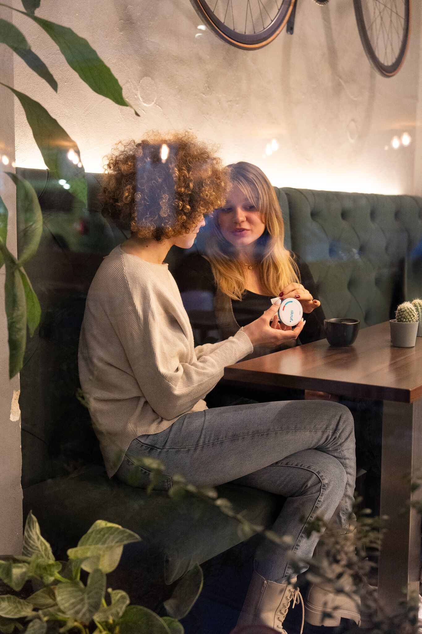 Zwei Frauen sitzen im Café und betrachten gemeinsam eine skruf.-Dose.