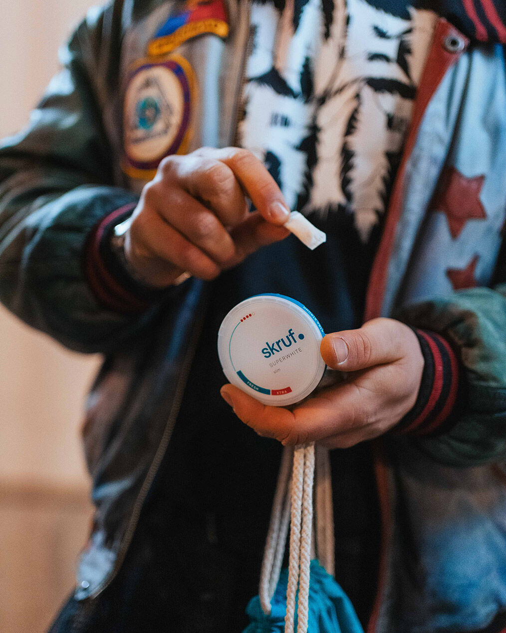 Mann nimmt Nikotinbeutel aus einer skruf Dose und hält den Beutel zwischen den Fingern