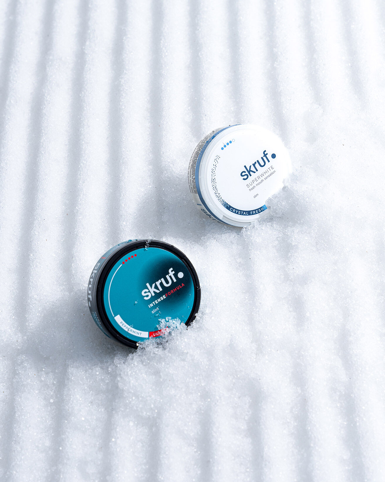 Zwei skruf Nikotinbeutel Dosen auf einer präparierten Skipiste