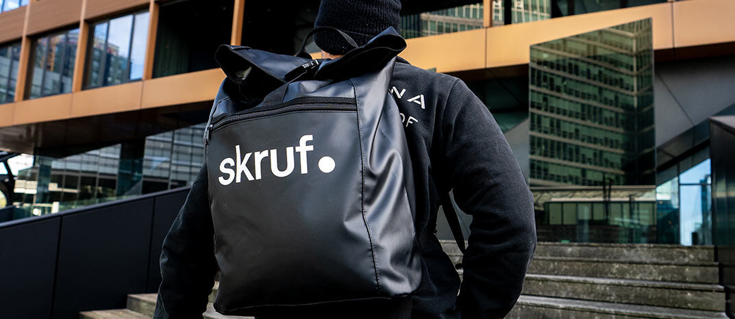 Schwarzer skruf Rucksack auf dem Rücken einer Person im urbanen Umfeld