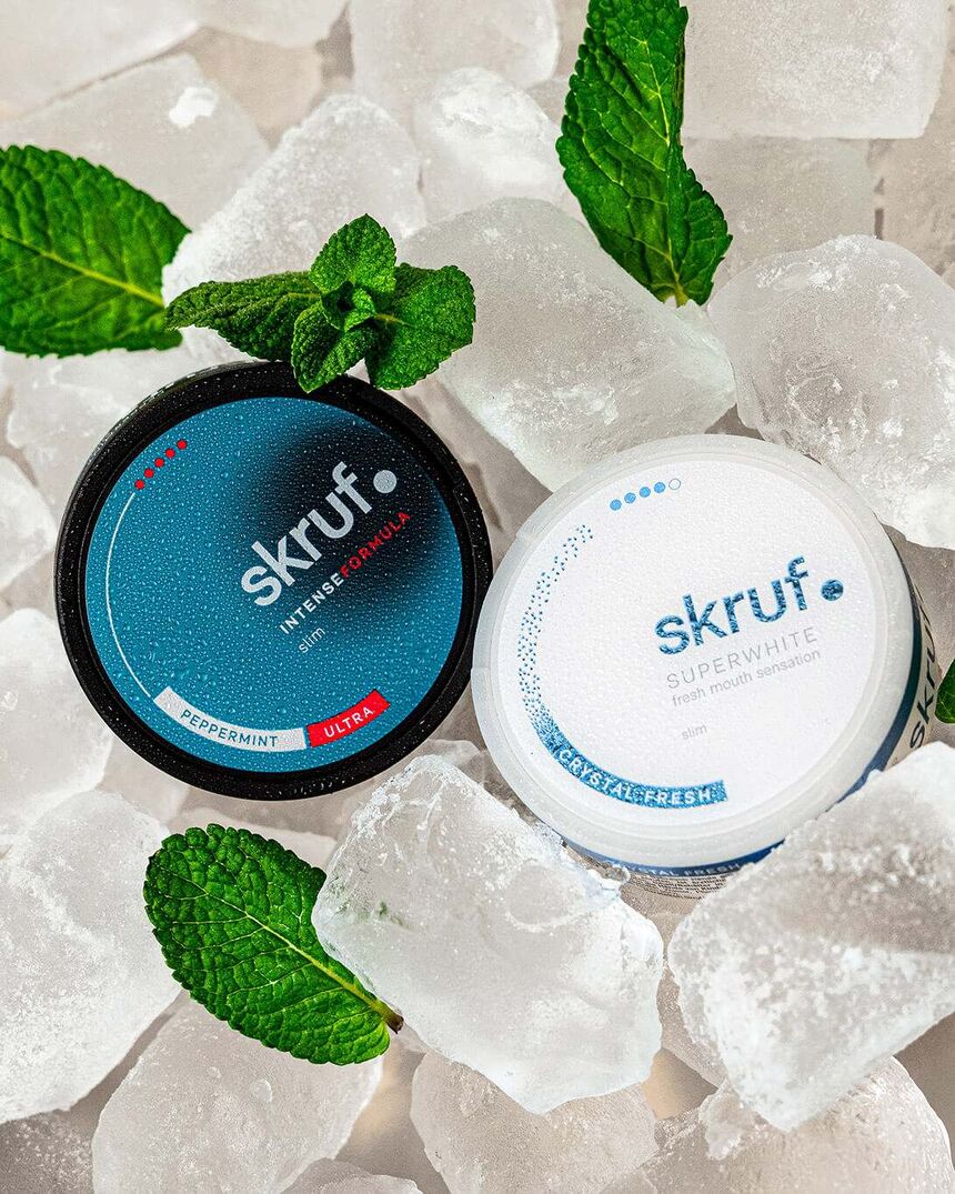 Skruf Intense Formula und Superwhite Dosen auf Eiswürfeln mit Minze.